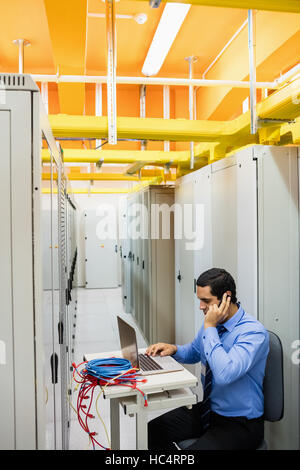 Technician talking on mobile phone in server room Stock Photo