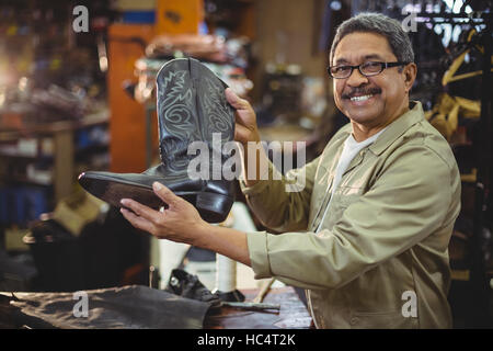Portrait of smiling shoemaker holding a leather boot Stock Photo