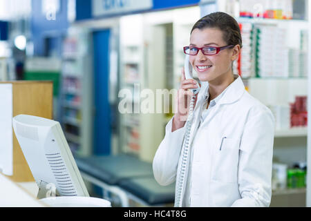 Smiling pharmacist talking on phone in pharmacy Stock Photo
