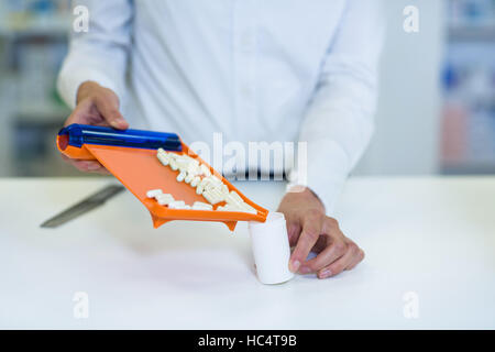 Pharmacist putting pill in container at pharmacy Stock Photo