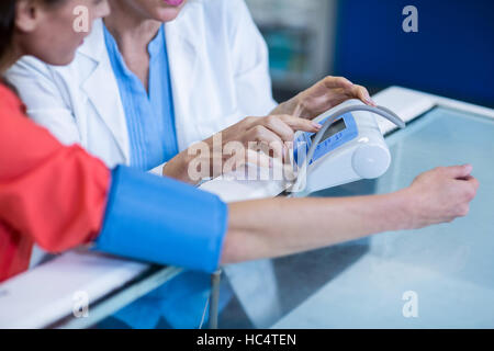 Pharmacist checking blood pressure of customer Stock Photo