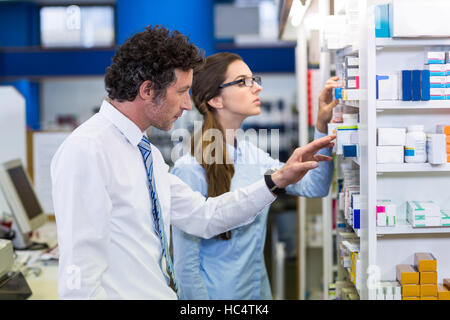 Pharmacists checking medicines on shelf in pharmacy Stock Photo