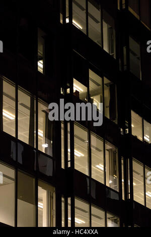 View of an office block in central London at night with windows glowing with light. Stock Photo