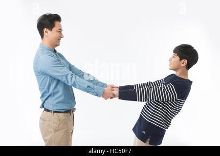 Side view of smiling middle aged father and adolescent son holding hands face to face Stock Photo