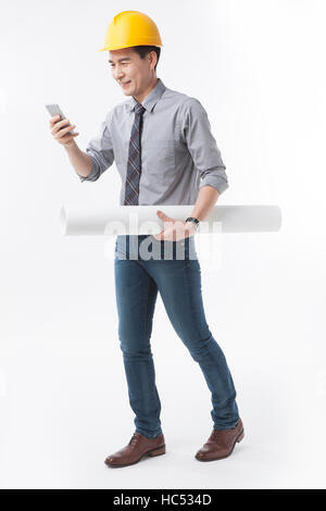 Side view of smiling architect walking using his smartphone Stock Photo