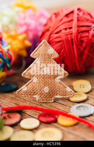 closeup of some cozy handmade christmas ornaments such as a fabric christmas tree and some christmas balls made with notions on a rustic wooden surfac Stock Photo