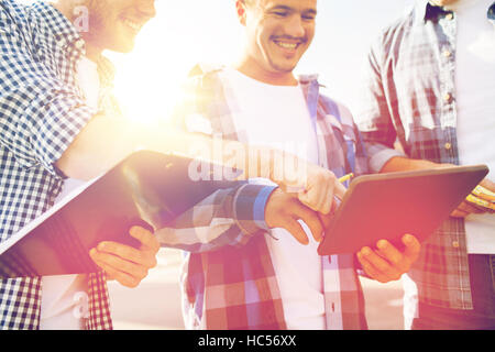 group of smiling builders with tablet pc outdoors Stock Photo