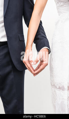 Just married couple holding hands and making heart shape with fingers Stock Photo