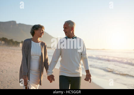 Portrait of romantic senior couple walking hand in hand on the beach. Loving mature couple having a walk on the sea shore. Stock Photo