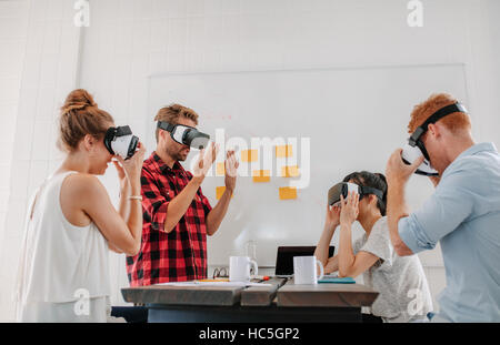 Business people using virtual reality goggles in meeting in office. Team of developers testing virtual reality headset. Stock Photo