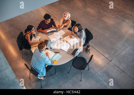 Top view of group of students sitting together at table. university students doing group study and smiling. Stock Photo