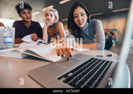 University students using laptop in a library. Young man and woman studying together. Stock Photo