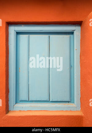 a blue wooden door or shutter in an orange wall Stock Photo