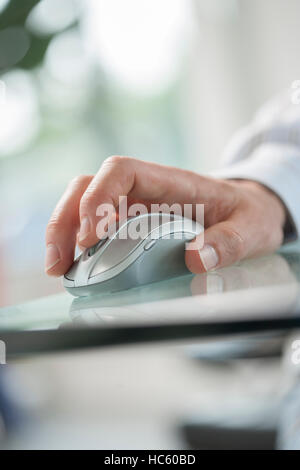 Image of a male hand clicking a cordless computer mouse on a green table Stock Photo