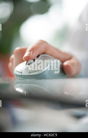man using his forefinger to control a cordless mouse on green glass table Stock Photo