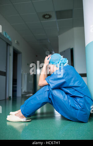 Sad surgeon sitting on floor in corridor Stock Photo