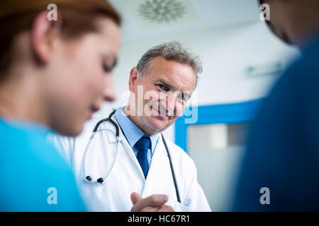 Portrait of smiling doctor standing with surgeons in corridor Stock Photo