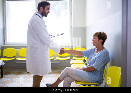 Doctor shaking hand with patient in waiting room Stock Photo