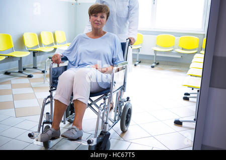 Doctor pushing senior patient on wheelchair Stock Photo