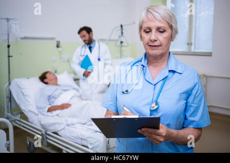 Nurse writing on clipboard Stock Photo