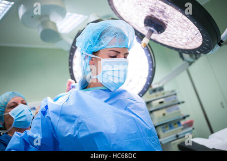Nurse helping a surgeon in wearing scrub Stock Photo
