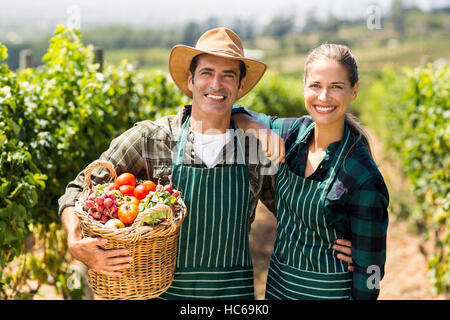 Portrait of happy farmer couple holding a basket of vegetables Stock Photo