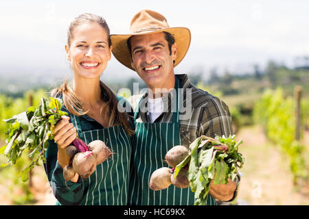 Portrait of happy farmer couple holding leafy vegetables Stock Photo