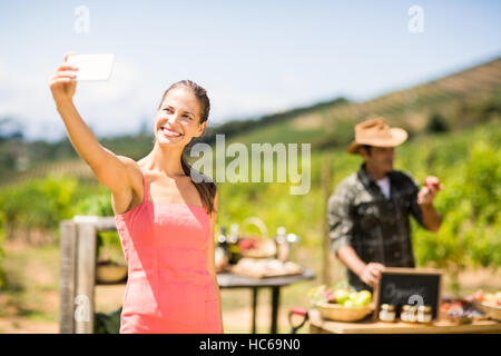 Female customer taking a selfie in front of vegetable stall Stock Photo