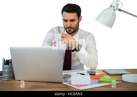 Businessman working on laptop in office while having coffee Stock Photo