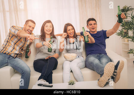 Friends Watching A TV In The Home Stock Photo