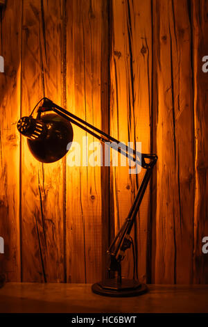 Table Top Lamp Lit Over a Wooden Textured Background. Copy Space. Stock Photo