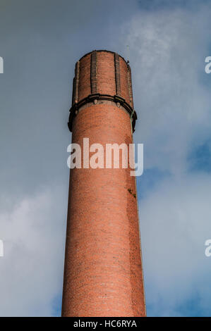 Red brick mill or factory chimney against a stormy sky Stock Photo