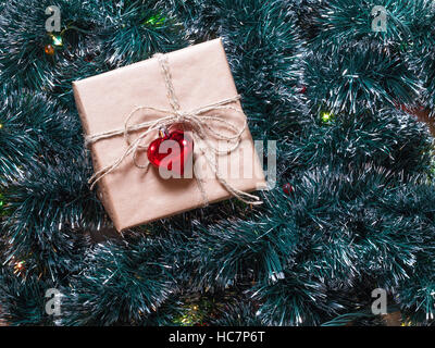 Christmas gift box on a fur-tree and garland background. Packaging holiday gifts. Stock Photo