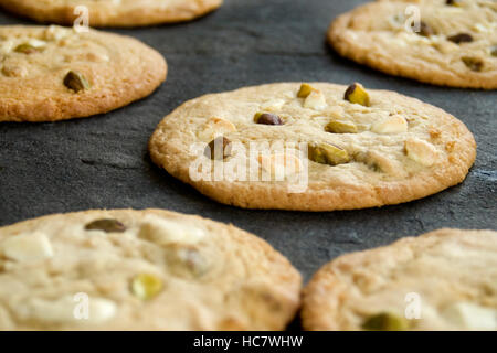 Home-Made Soft Chewy Cookies with White Chocolate Pieces and Pistachio Nuts, on Slate Stock Photo