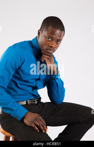Handsome black man sitting on a stool and looking thoughtfully at the camera Stock Photo