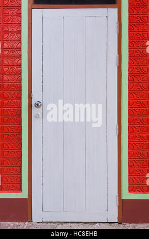 White vintage door and orange color paint brick wall, white simple style door and orange painted wall with handle and lock Stock Photo