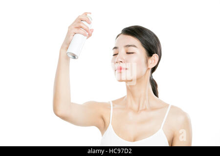 Side view portrait of young smiling woman spraying mist on her face closing eyes Stock Photo
