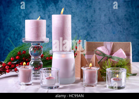 Festive glamorous holiday Christmas table setting with pink candles, gift against a blue background. Stock Photo