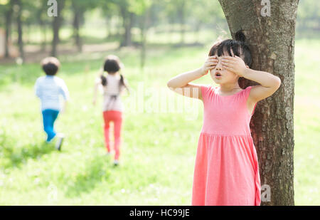 Chidren playing hide-and-seek in field Stock Photo