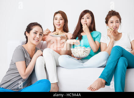 Four young women watching television eating snacks