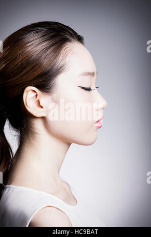 Side view portrait of young Korean woman with ponytail and black mascara closing eyes Stock Photo