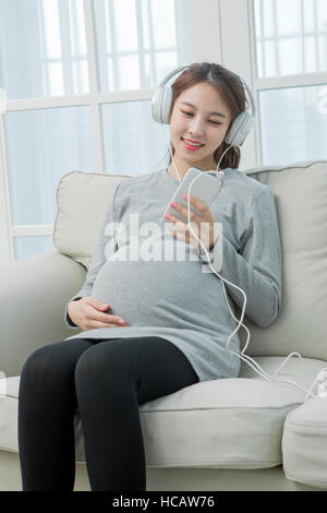 Smiling pregnant woman listening to music Stock Photo