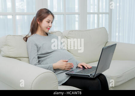 Side view of smiling pregnant woman using notebook computer Stock Photo