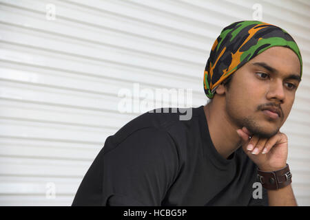 Close-up of  young Indian boy with hand on chin thinking Stock Photo