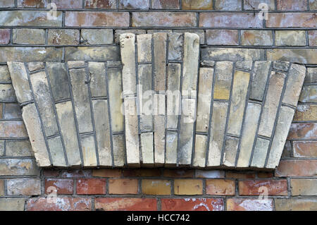 Decorative element in the form of a crown made from yellow bricks on an old aged  wall Stock Photo