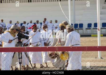 Musicians playing and singing traditional Omani music with instruments at a camel race in the desert in Oman Stock Photo