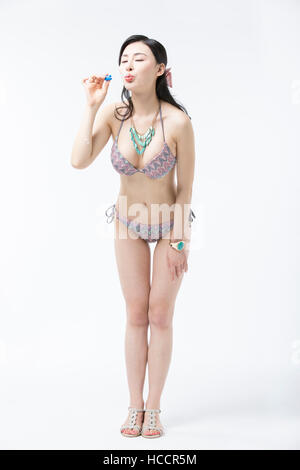 Young woman in bikini standing blowing bubbles Stock Photo