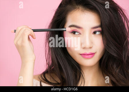 Portrait of young woman using eyeshadow brush Stock Photo