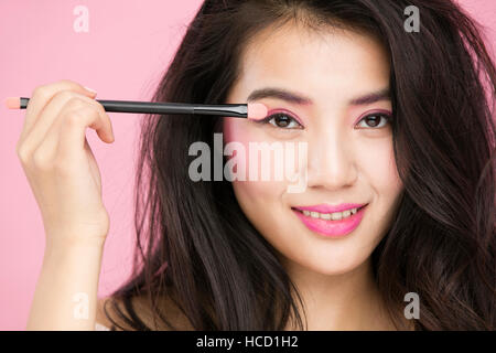 Portrait of young smiling woman using eyeshadow brush Stock Photo