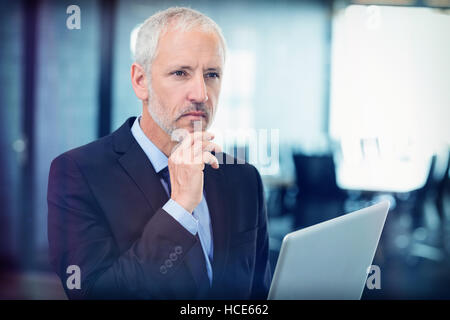Thoughtful businessman thinking while working on laptop Stock Photo